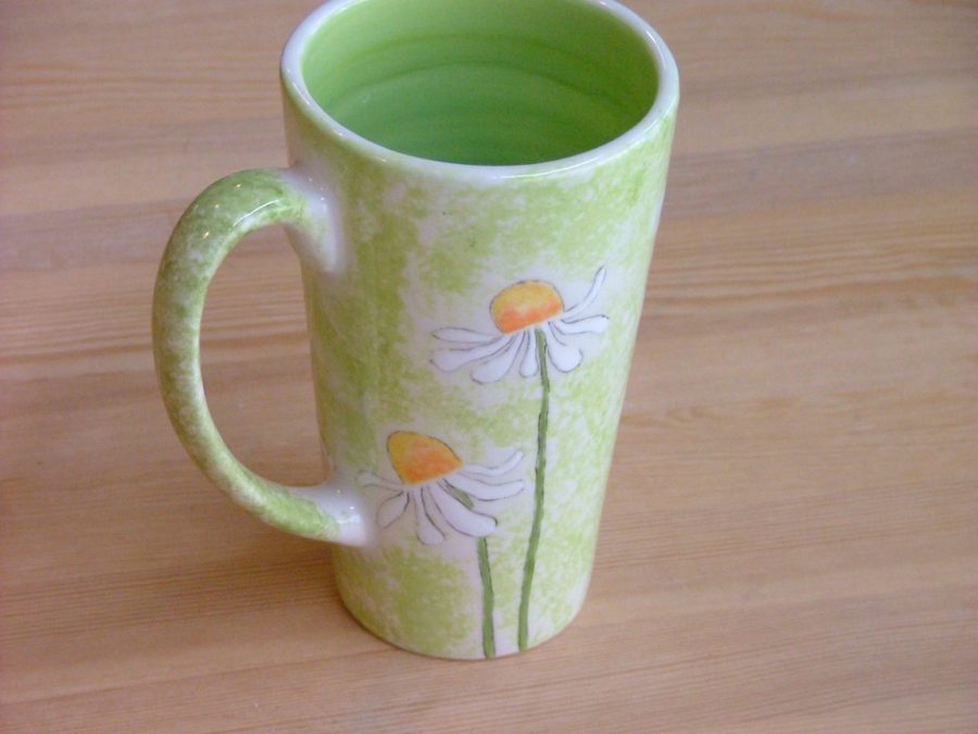 Grün bemalte Tasse mit handgemalten Gänseblümchen